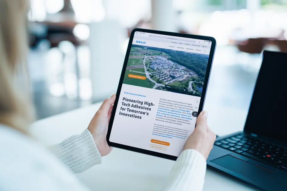 Woman at desk with iPad in her hand - DELO website on screen